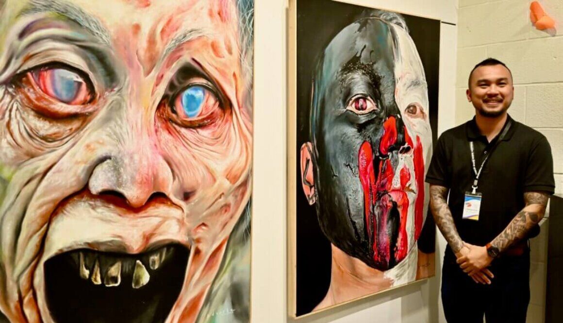 Filipino artist Peter Duarte stands beside two of his paintings.