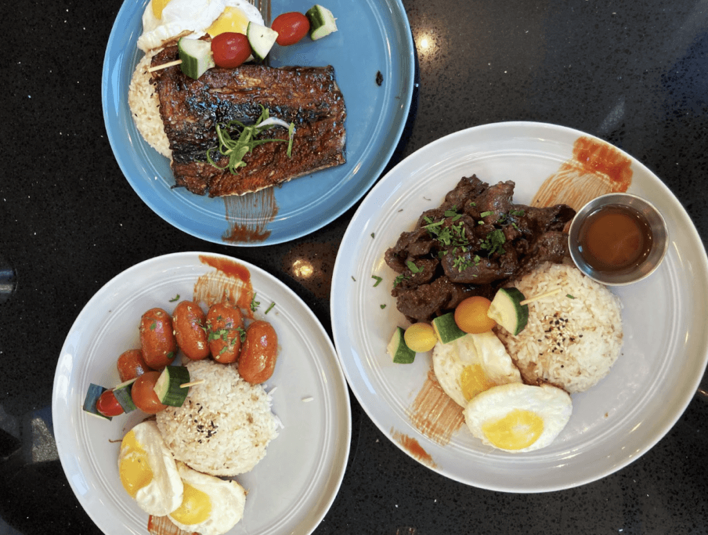 Three plates with rice, eggs, fish, Filipino sausage and meat.